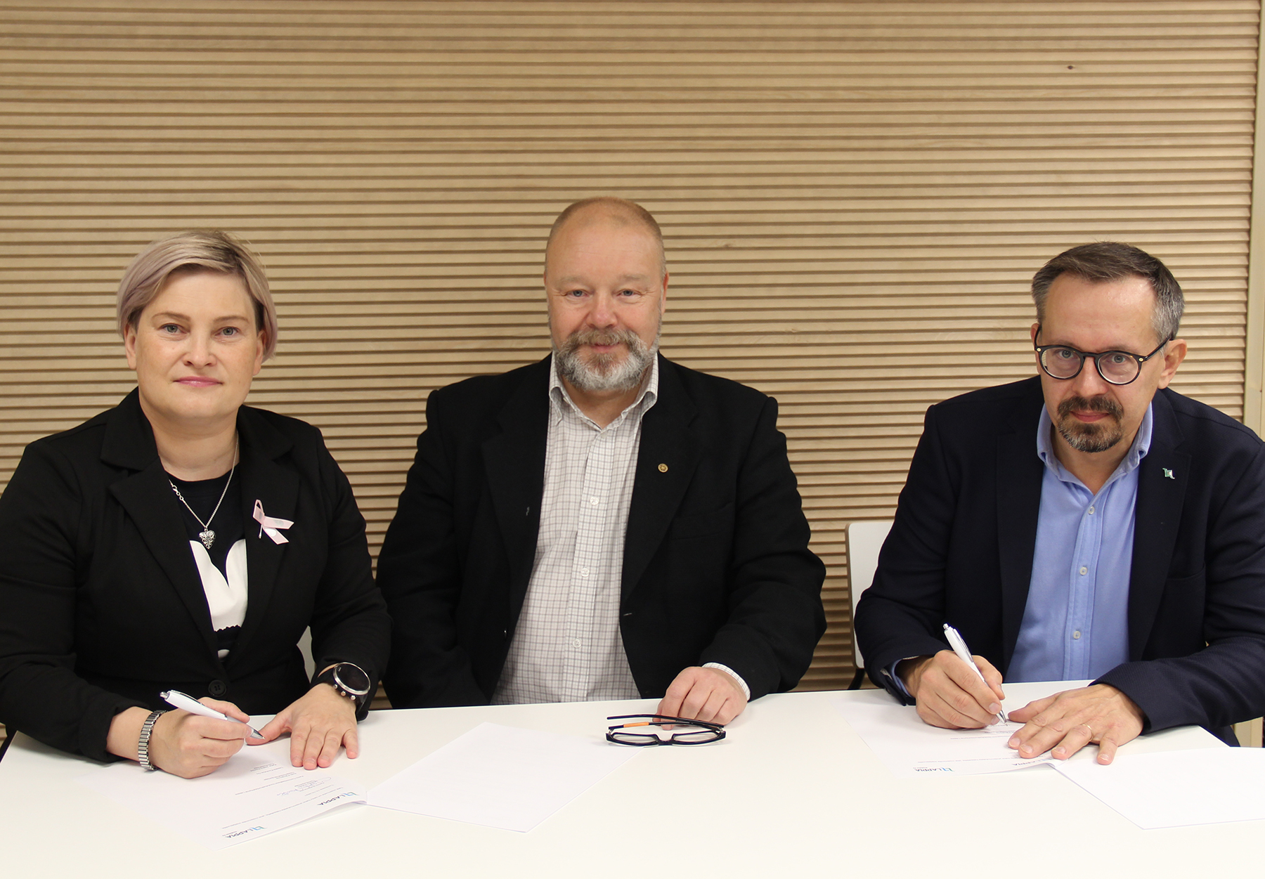 Kuvassa henkilöt Katja Jaako-Körkkö, Markku Rautio ja Antti Päivärinta pöydän ääressä allekirjoittamassa sopimusta