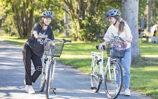 Kaksi opiskelijatyttöä lähdössä pyöräilemään.