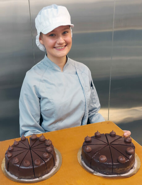 Kuvassa elintarvikealan opiskelija esittelemässä valmistamiaan kakkuja
