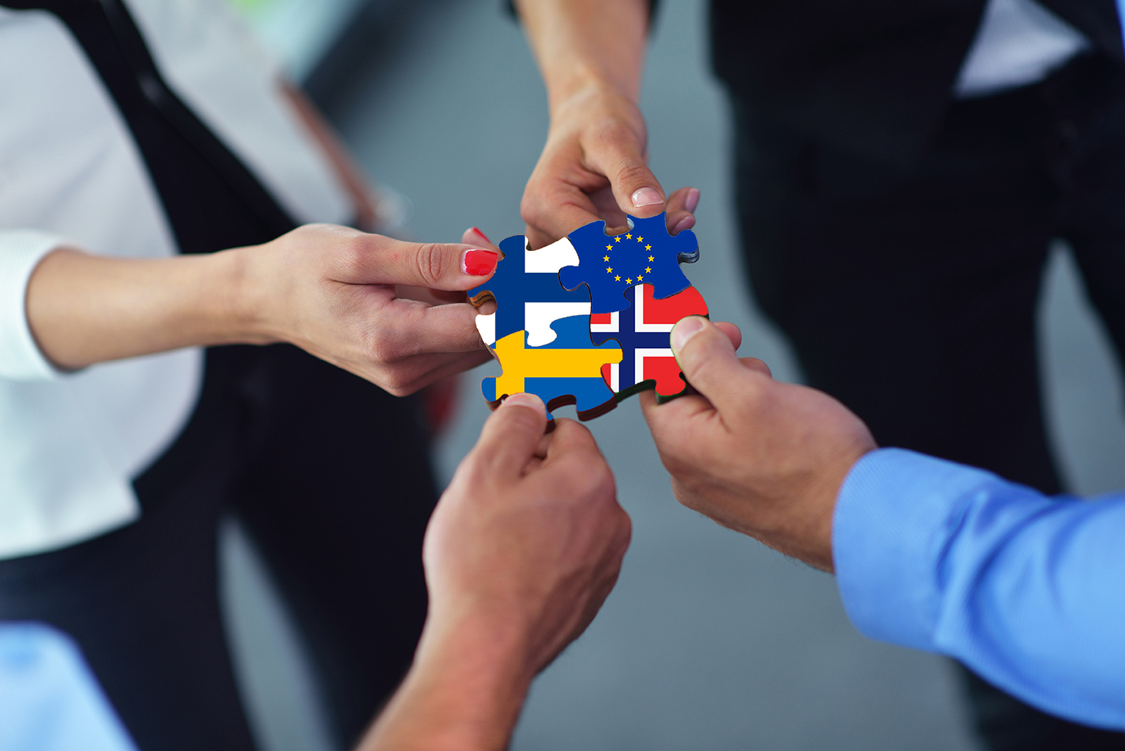 Ihmisten käsissä EU:n, Suomen, Ruotsin ja Norjan lippusymbolit.