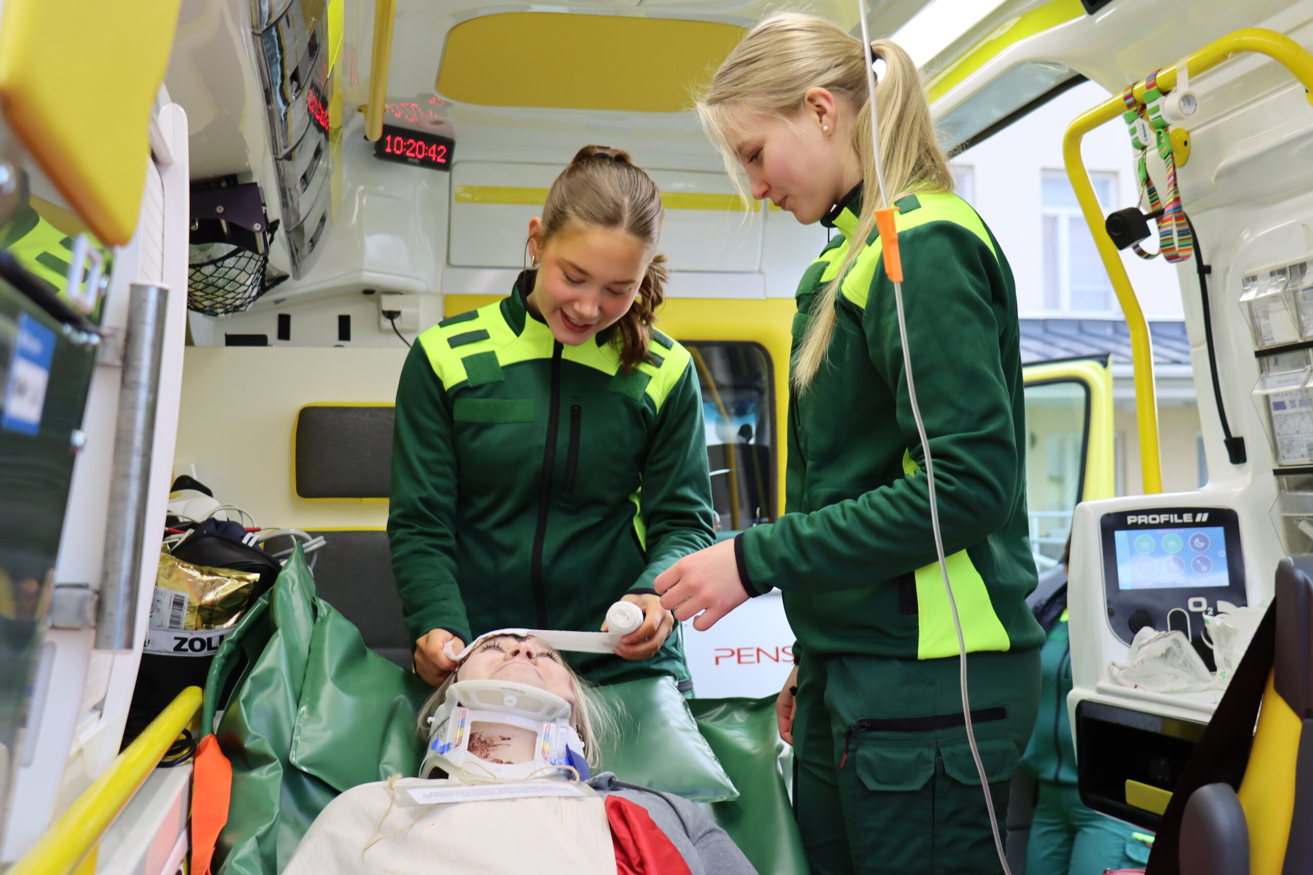 Ensihoidon opiskelijat esittelevät ambulanssissa hoitotoimenpiteitä.