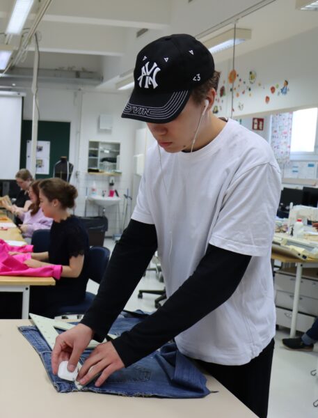 Kuvassa tekstiili- ja muotialan opiskelija mittomassa farkkuja