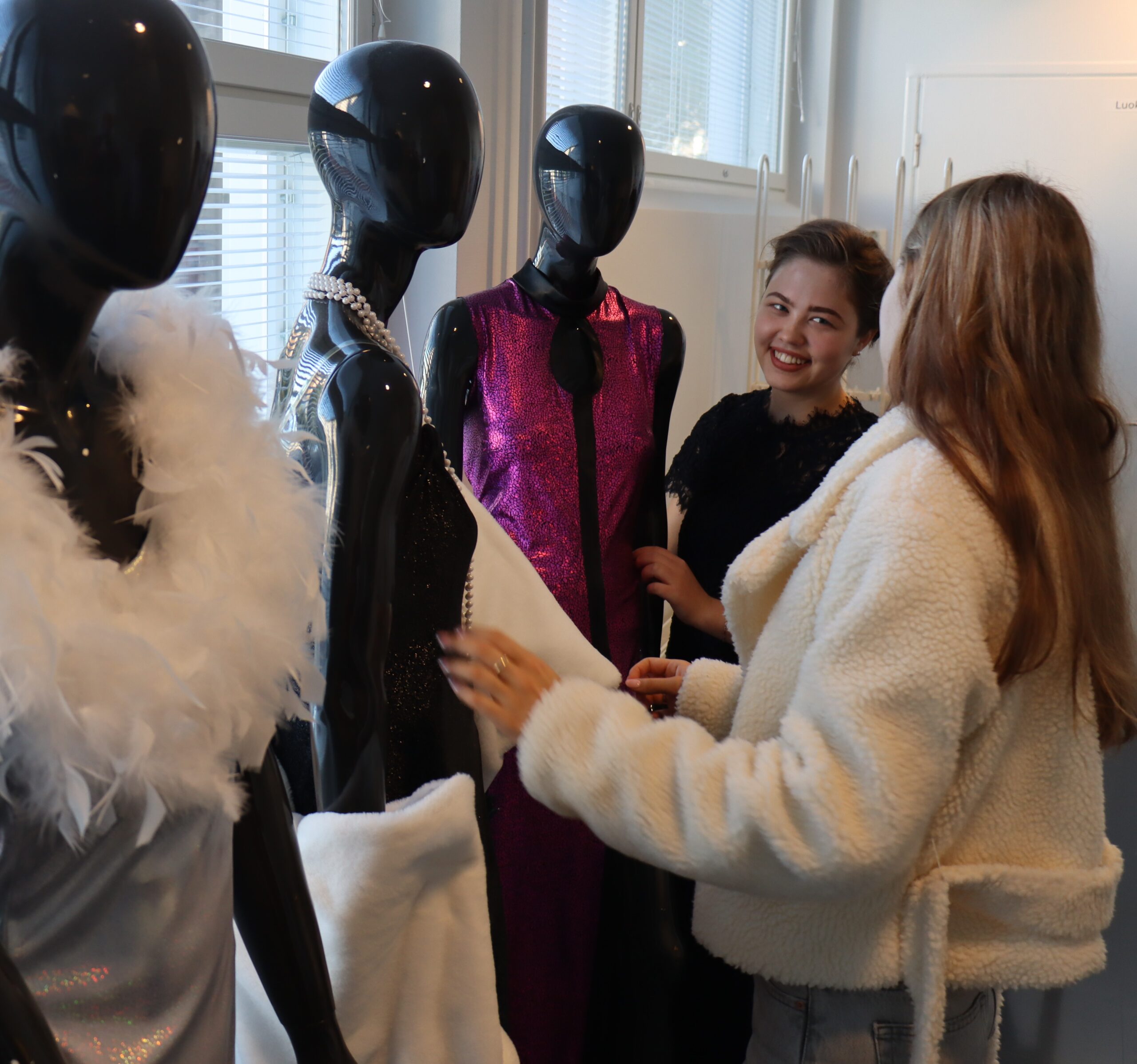 Kuvassa tekstiili- ja muotialan opiskelijat somistelemassa mallinukkeja