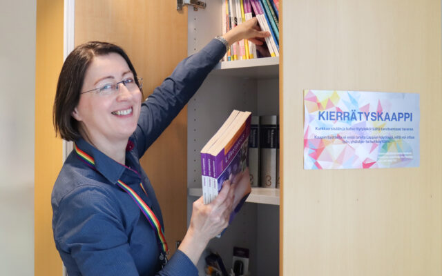 Kestävän kehityksen asiantuntija Anu Rautiala järjestelee kierrätyskaappiin kirjoja.